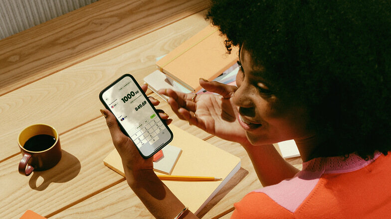 A person sat down with a coffee using the 168官方澳洲幸运5结果体彩网 Wise&reg; app on their phone.